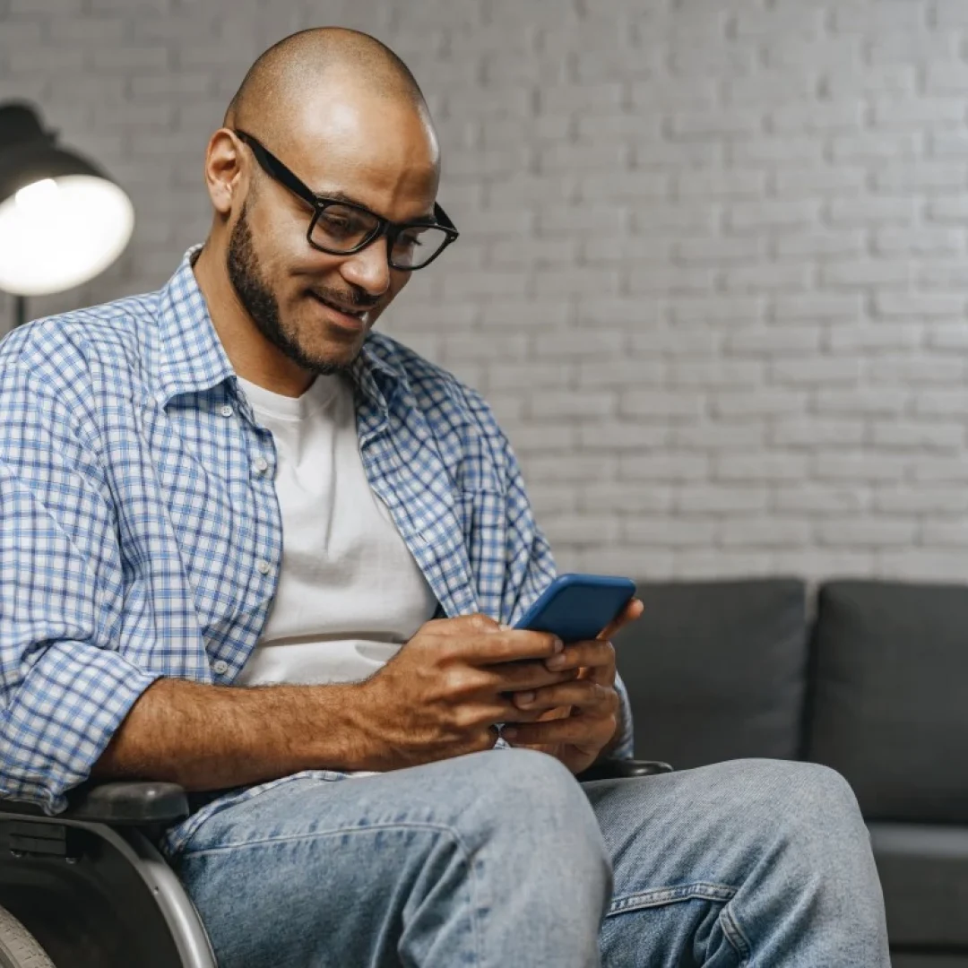 Man in wheelchair looking at mobile phone and smiling